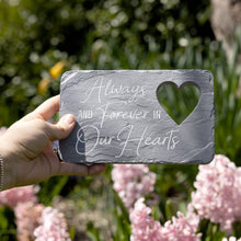 Load image into Gallery viewer, Slate memorial garden stone with engraved text and heart cutout held against garden background