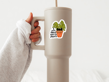 Load image into Gallery viewer, Hand holding beige travel mug with cute cat and plant sticker saying just need cats and plants