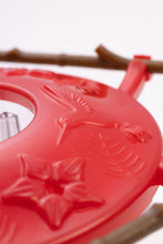 Load image into Gallery viewer, Red plastic hummingbird feeder with decorative floral design and feeding ports
