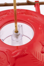 Load image into Gallery viewer, Red hummingbird feeder with clear nectar reservoir and wooden perch stick mounted on stand