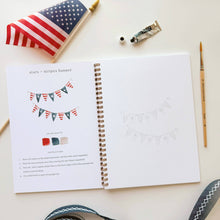 Load image into Gallery viewer, Open watercolor workbook showing stars and stripes banner tutorial with American flag and art supplies