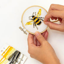 Load image into Gallery viewer, Hands working on small bee cross stitch embroidery in wooden hoop with colorful thread