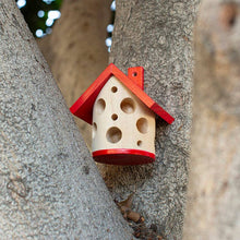 Load image into Gallery viewer, Red and natural wood ladybug house with circular holes mounted on tree trunk