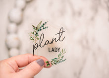 Load image into Gallery viewer, Hand holding clear vinyl sticker with 'plant lady' text and botanical greenery design