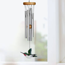 Load image into Gallery viewer, Wind chime with silver tubes, wooden top, and decorative hummingbird striker hanging indoors