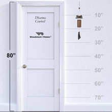 Load image into Gallery viewer, Dharma Cowbell wind chime with bronze tube and black clapper shown against height measurement scale