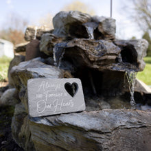 Load image into Gallery viewer, Memorial garden stone with heart cutout reading 'Always and Forever in Our Hearts' placed near water fountain