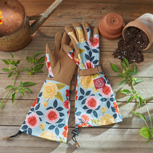 Load image into Gallery viewer, Floral patterned gardening gloves with extended arm protection laid on wooden surface with garden tools
