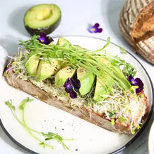 Load image into Gallery viewer, Fresh daikon radish microgreens sprouting on avocado toast with purple flowers