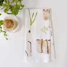 Load image into Gallery viewer, White cotton tea towel with botanical wildflower illustrations and woven basket design