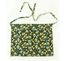 Load image into Gallery viewer, Half apron with dark green background featuring yellow wildflowers and green botanical print pattern