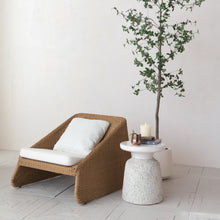 Load image into Gallery viewer, Brown wicker lounge chair with white cushions next to ceramic side table and plant