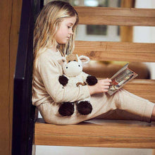 Load image into Gallery viewer, Young girl reading while cuddling cream and brown spotted cow plush toy on wooden stairs