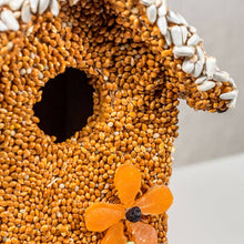Load image into Gallery viewer, Bird-shaped cottage feeder covered in golden seeds with white sunflower seeds and orange dried fruit decoration