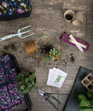Load image into Gallery viewer, Garden labeling supplies with seed packets, plant markers, and gardening tools on wooden surface