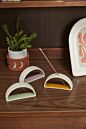 Load image into Gallery viewer, Curved brass-colored incense holder with geometric arch design on wooden surface
