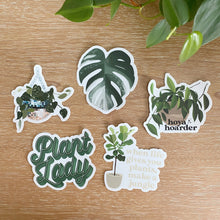 Load image into Gallery viewer, Collection of five plant-themed vinyl stickers featuring houseplants and botanical sayings on wood surface