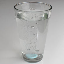 Load image into Gallery viewer, Two fizzing plant fertilizer tablets dissolving in clear glass of water