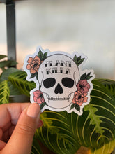 Load image into Gallery viewer, Hand holding Plant Killer skull sticker with pink flowers and green leaves against houseplant background