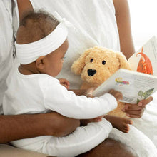 Load image into Gallery viewer, Child in white headband reading book while cuddling golden plush dog toy