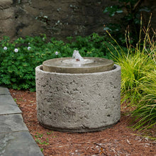 Load image into Gallery viewer, Cylindrical concrete water fountain with center spout in garden setting with plants