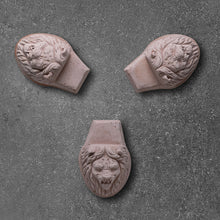 Load image into Gallery viewer, Three terracotta pot feet with decorative lion face carvings on dark surface