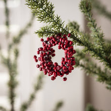 Load image into Gallery viewer, Close-up detail of red berry wreath ornament hanging on evergreen pine branch