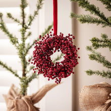 Load image into Gallery viewer, Red berry wreath hanging by red ribbon near Christmas trees wrapped in burlap
