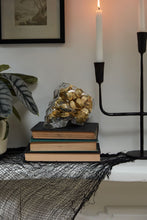 Load image into Gallery viewer, Glass skull-shaped candy dish filled with gold foil chocolates on stacked vintage books