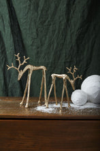 Load image into Gallery viewer, Two gold metallic reindeer figurines with antlers on wooden surface with artificial snow