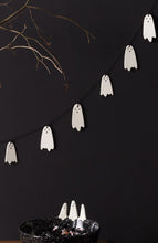 Load image into Gallery viewer, White ceramic ghost garland strung on black cord against dark wall with Halloween candy bowl