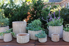 Load image into Gallery viewer, Collection of ribbed terracotta Pilar Bowl planters in various sizes on outdoor deck with herbs and lavender