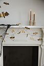 Load image into Gallery viewer, Gold metallic bat garland draped across a white fireplace mantel with candles