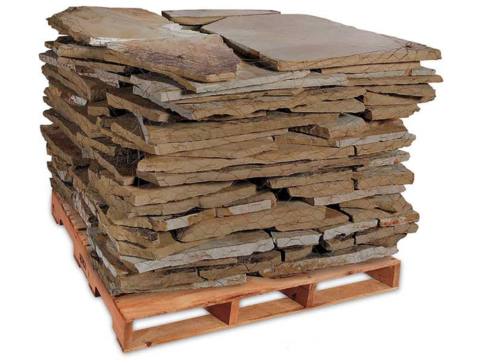 Stack of natural brown and tan flagstone pieces on wooden pallet for landscaping